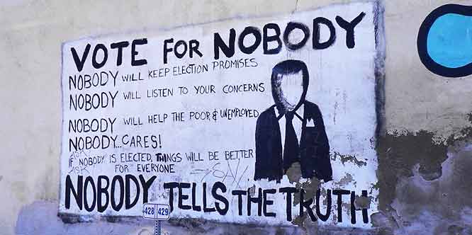 Fresque murale peinte au pochoir : « VOTE FOR NOBODY. Nobody will keep election promises, nobody will listen to your concerns, nobody will help the poor & unemployed, nobody cares ! If nobody is elected, things will be better for everyone. Nobody tells the truth. » À droite, la silhouette d'un homme en costume au visage effacé.